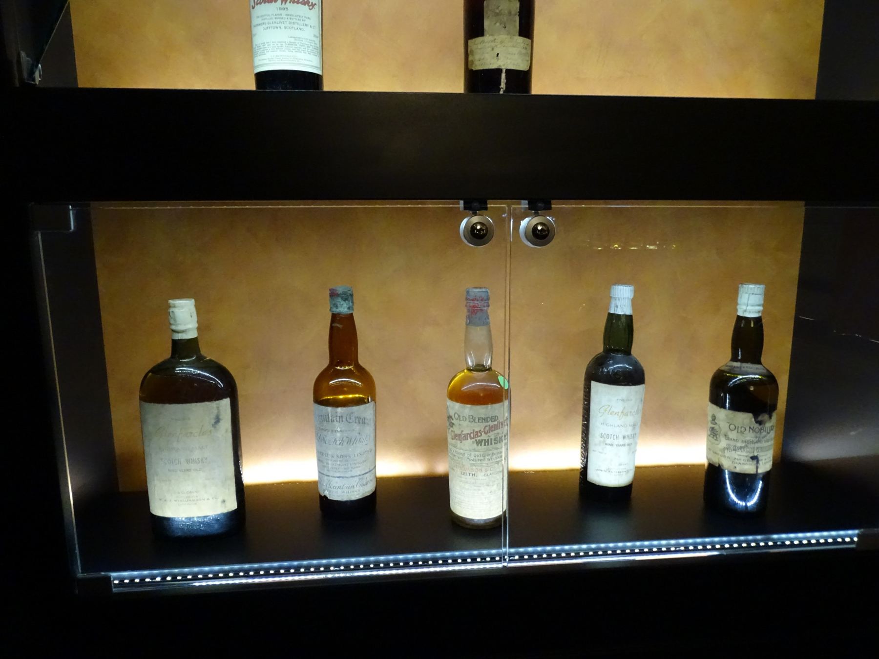 Old bottles on a lit glass shelf in the exhibition